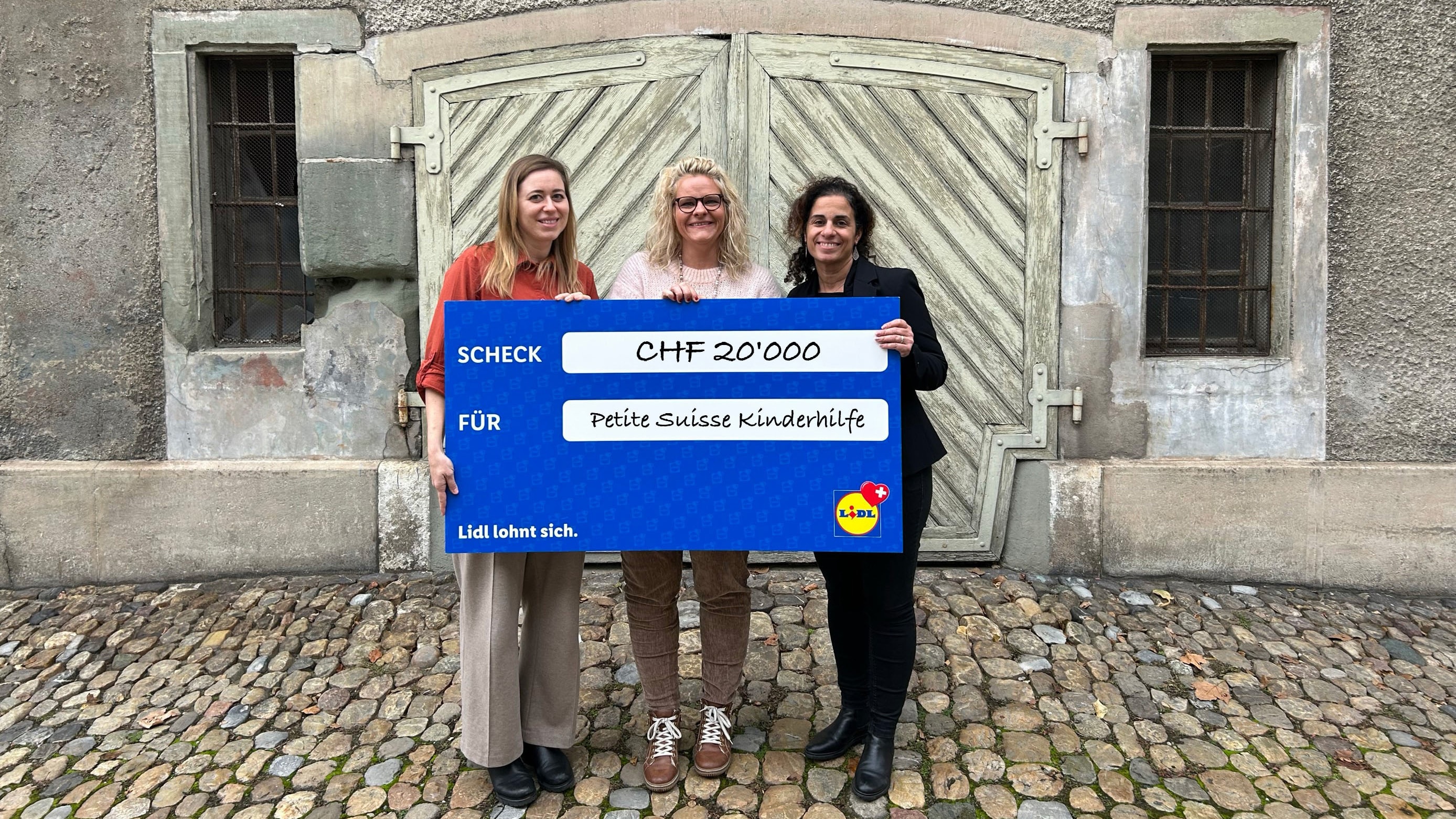 Petite Suisse Kinderhilfe erhält einen blauen Scheck von 20'000 Franken.